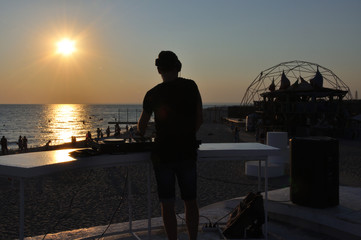 DJ plays music on the beach at sunset