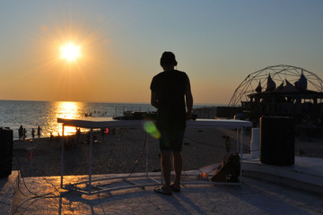 DJ plays music on the beach at sunset