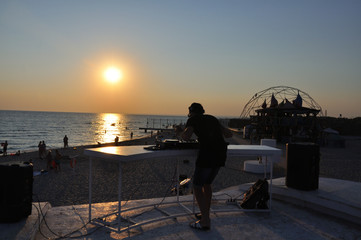 DJ plays music on the beach at sunset