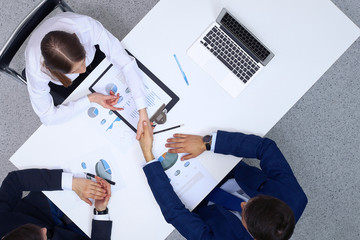 Business people shaking hands after analyzing financial documents, view from above. Business team at meeting