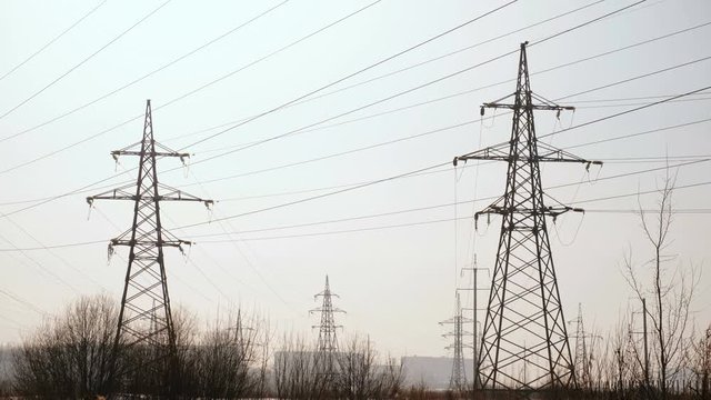 High-voltage towers, transmission line in winter city background. Camera moving from bottom to up.