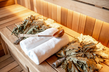 Bath brooms with towels and scoop on the bench at the russian traditional sauna