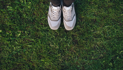 Sports womens gray shoes sneakers on fresh green grass. Top view.