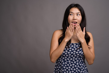 Asian woman wearing blue dress against gray background