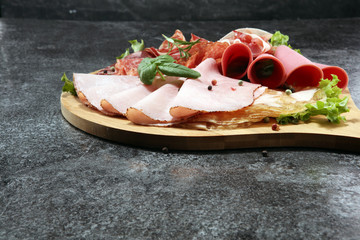 Food tray with delicious salami, pieces of sliced ham, sausage and salad. Meat platter with selection.