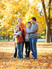 Fototapeta premium Happy family walks in autumn city park. Children and parents posing, smiling, playing and having fun. Bright yellow trees.