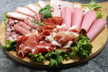 Food tray with delicious salami, pieces of sliced ham, sausage and salad. Meat platter with selection.
