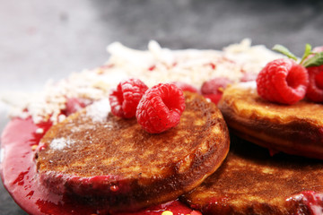 Pancakes with berries and maple syrup on rustic table