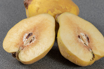 Halved quince in front of a quince in the kitchen 