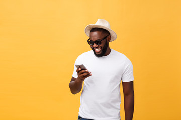Cheerful African American man in white shirt using mobile phone application. happy dark skinned hipster guy read news from social network in mobile phone.