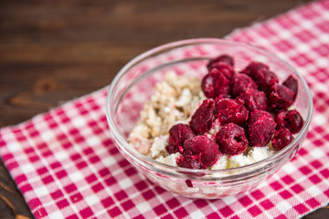 Oatmeal with cottage cheese and cherry on wooden background. Summer healthy breakfast.