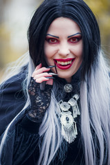 Image of smiling vampire girl with stream of blood near her mouth