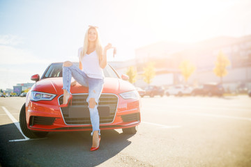 Photo of young woman with keys standing near red car on