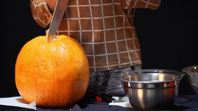 Scary video of a young girl using a big knife to try and cut the top off of a pumpkin.  She uses both hands to stab into the pumpkin without holding the gourd still.  The squash is very unstable.