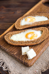 Fried eggs in bread with cheese on wooden background. Healthy breakfast