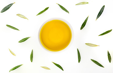 Bowl of extra virgin olive oil with olive leaves. Zenital plane on white background.