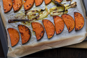 Appetizing roasted pumpkin slices on baking tray. With onion.