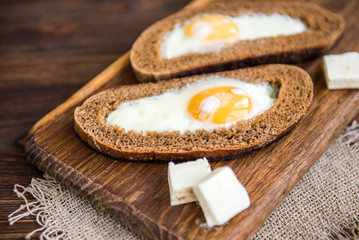 Obraz na płótnie Canvas Fried eggs in bread with cheese on wooden background. Healthy breakfast