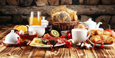 breakfast on table with bread buns, croissants, coffe and juice on christmas day. xmas holiday morning.