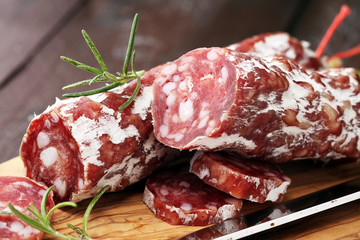 thinly sliced salami on a wooden texture on the background.