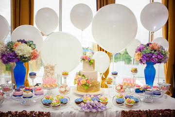 Candy bar on golden wedding party with a lot of different candies, cupcakes, souffle and cakes. Decorated in brown and purple colors, nature and eco theme, indoor