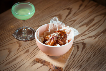 fried chicken wings with sesame in the plate and green cocktail with lime on the table 