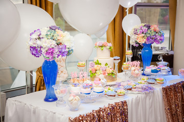 Candy bar on golden wedding party with a lot of different candies, cupcakes, souffle and cakes. Decorated in brown and purple colors, nature and eco theme, indoor