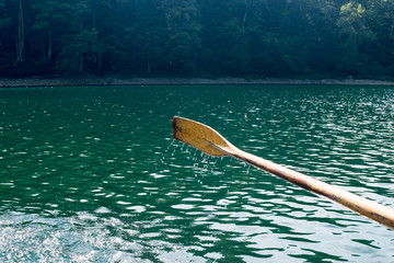 Oar of boat touching water and causing splash and ripples in the water A wooden paddle on a boat Blade of wooden kayak or canoe paddle Water splash  
