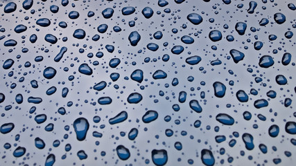 After the rain water drops on the blue metal background