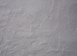 light grey rough textured wall background with an uneven worn surface with cracks and a weathered surface