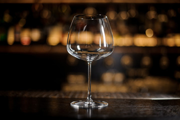 Transparent empty wine glass standing on the bar counter