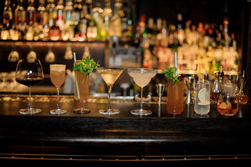 Many delicious cocktails in a line on the bar counter