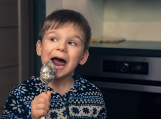 Naklejka premium Child cooking in the kitchen. Little boy helping mother to prepare food