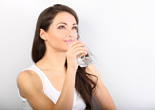 Positive happy smiling woman with healthy skin and long curly hair drinking pure water on white background. Closeup portrait