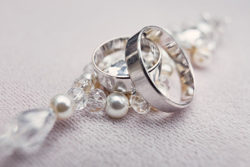 Classy silver wedding rings made of white gold lie on the crystal bracelet