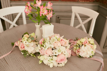 Three wedding bouquets of pink and beige flowers lie on the dinner table