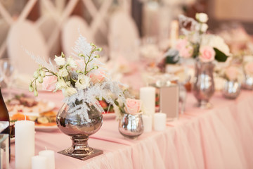 Wedding table festive service. Dinner table decorated with silver statues and vases with white flowers and feathers