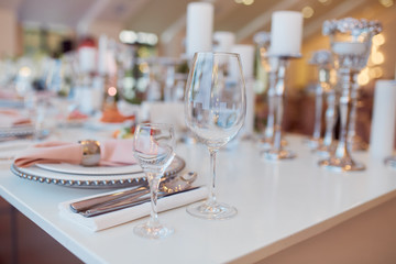 Wedding table service. Plates, glasses and flowers served on pink cloth