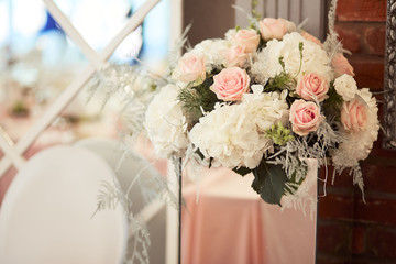 Wedding table festive service. Dinner table decorated with silver statues and vases with white flowers and feathers