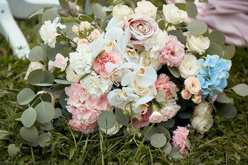 Tender wedding bouquet made of blue, pink and white roses stands on the glass table outside