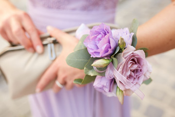 Woman with violet bracelet of flowers holds little bag in her hand