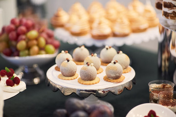 Wedding candy bar. Dishes with delicious sweets, cookies and chocolate cakes stand on the dinner table