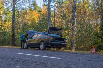 Portrait of beautiful young woman using her mobile phone calls for assistance for car.