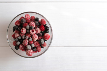 the frozen berries raspberry and currant in a glass plate on a white background
