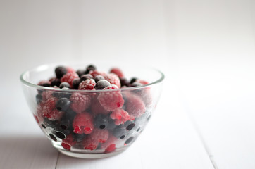 the frozen berries raspberry and currant in a glass plate on a white background