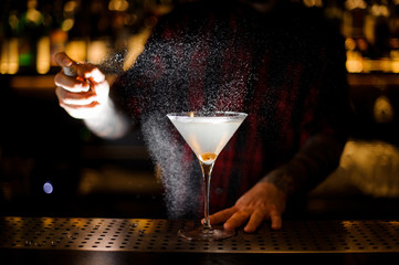 Bartender spraying with essence to a Dirty Martini cocktail