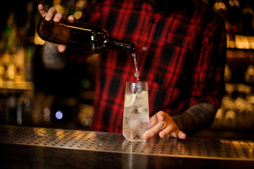 Fototapeta na wymiar Bartender pourring an alcohol making a Tom Collins cocktail