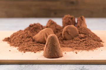 Chocolates with a sprinkling of cocoa powder on wooden background.