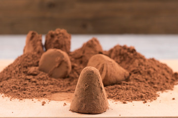 Chocolate truffle sprinkled with cocoa powder on the background of a bunch of candy powder.