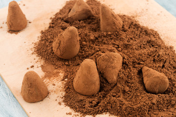 Chocolate truffles in the process of sprinkling cocoa powder.